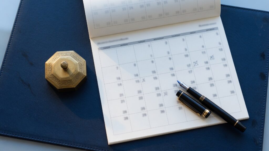 Forward-Flow Debt Sales: The Terms to Write Before the First Month 1 Calendar and pen on a navy blotter with no dates readable, suggesting a forward-flow schedule